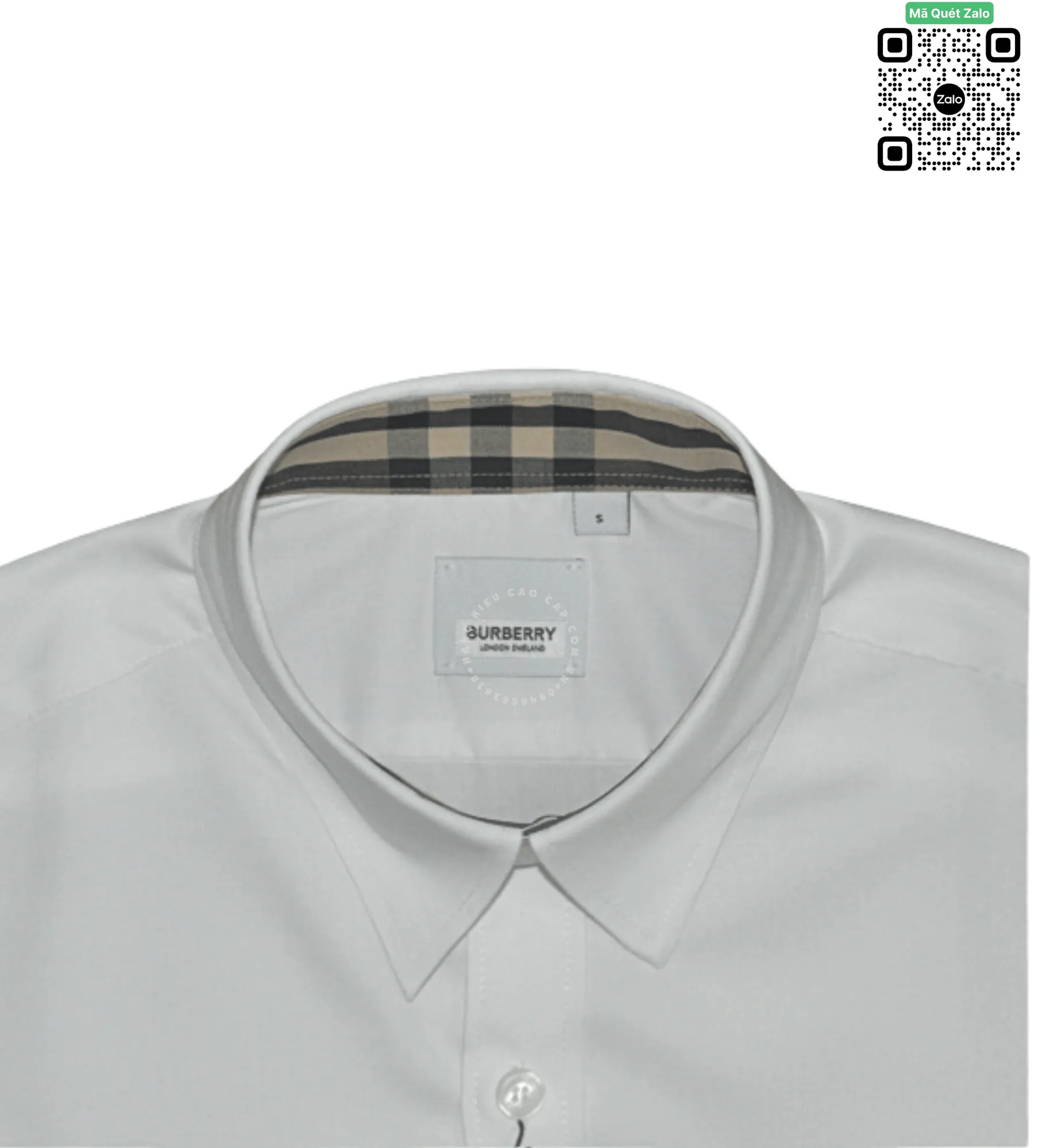 Ảnh chụp sát góc chính diện cổ bẻ của áo sơ mi trắng, để lộ phần tem mác cổ in chữ Burberry London England sắc nét và phần viền phía trong được lót vải họa tiết kẻ sọc màu nâu beige đặc trưng.